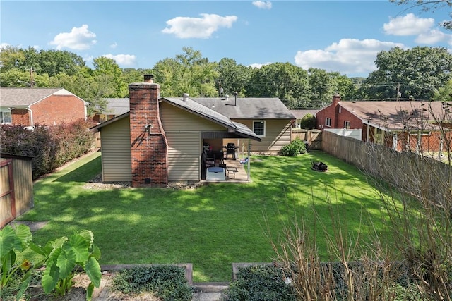 back of house with a fenced backyard, a patio, a chimney, and a lawn