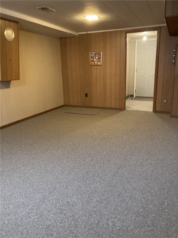 finished basement featuring wood walls, baseboards, and visible vents