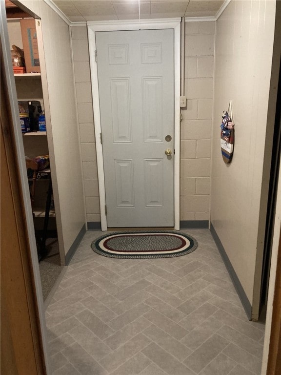 interior space featuring crown molding, concrete block wall, and baseboards