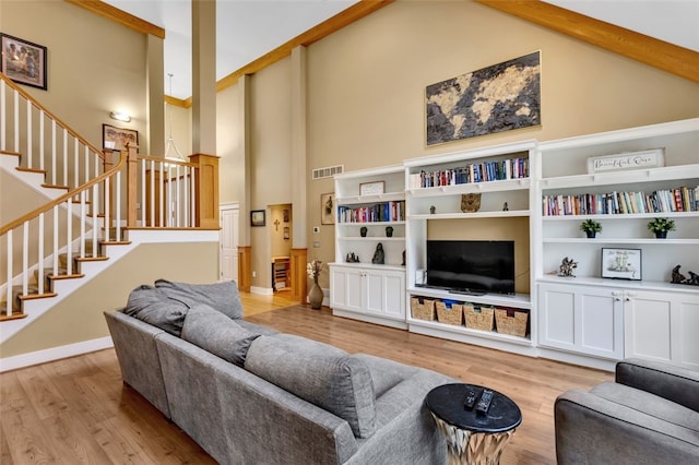 living area featuring visible vents, light wood-style flooring, high vaulted ceiling, baseboards, and stairs