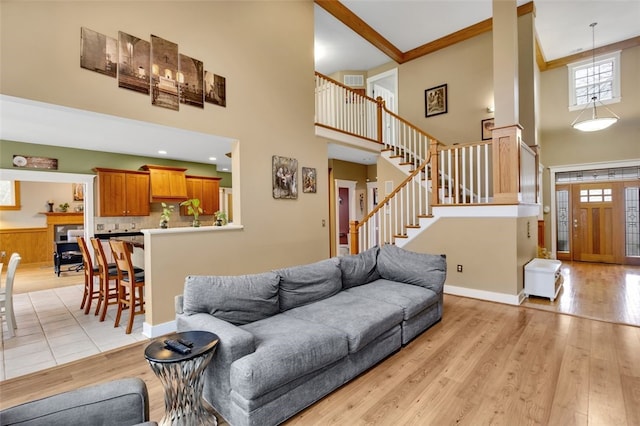 living room with light wood finished floors, baseboards, stairs, and a high ceiling