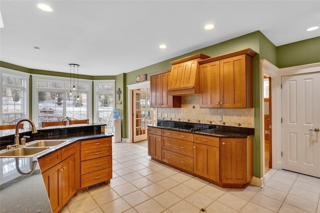 kitchen with light tile patterned floors, black electric cooktop, a sink, decorative backsplash, and brown cabinets