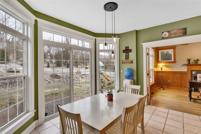 dining area with wainscoting, wood walls, and light tile patterned flooring