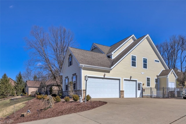 view of home's exterior featuring concrete driveway, stone siding, roof with shingles, an attached garage, and fence