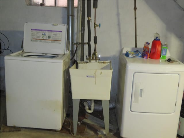 clothes washing area featuring laundry area, washing machine and dryer, and a sink