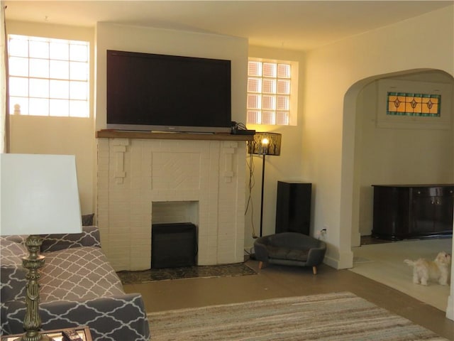 living area featuring arched walkways, a fireplace, and a wealth of natural light