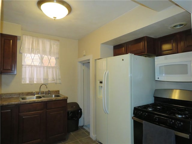 kitchen with white microwave, tile patterned flooring, dark brown cabinetry, a sink, and stainless steel gas range