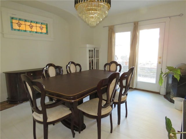 dining space with an inviting chandelier, light wood-style flooring, arched walkways, and a wealth of natural light