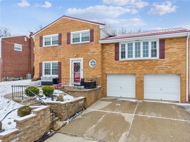 tri-level home with a garage, driveway, brick siding, and central AC unit