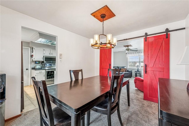 dining space with a barn door, ceiling fan with notable chandelier, and light colored carpet