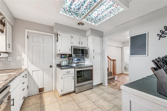 kitchen with light tile patterned floors, visible vents, appliances with stainless steel finishes, and white cabinets