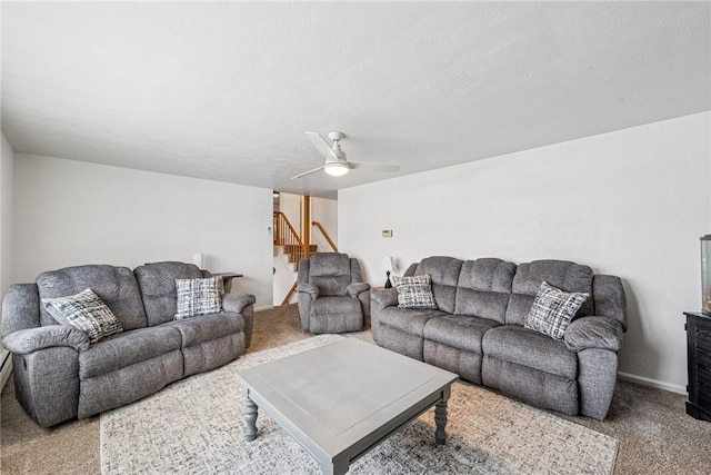 carpeted living area featuring stairway, a ceiling fan, and baseboards