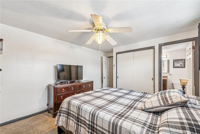 carpeted bedroom with ensuite bathroom, a closet, a ceiling fan, and baseboards