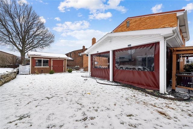 snow covered back of property with an outdoor structure