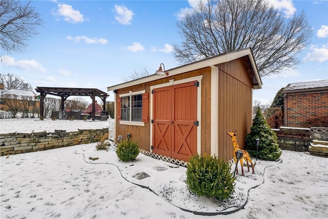 snow covered structure with a shed, a pergola, and an outdoor structure