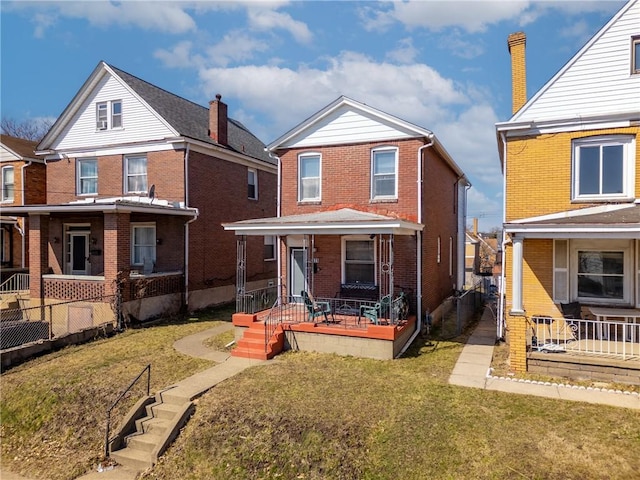 view of front of property with covered porch, brick siding, a front yard, and fence