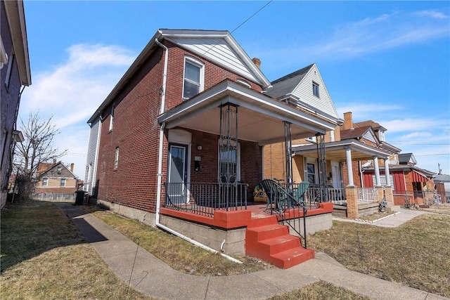 view of front of property with covered porch, brick siding, and a front lawn