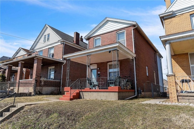 view of front facade with covered porch, brick siding, and a front lawn