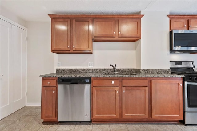 kitchen with appliances with stainless steel finishes, brown cabinetry, and a sink