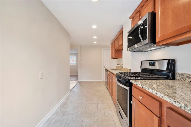 kitchen featuring recessed lighting, baseboards, appliances with stainless steel finishes, brown cabinets, and light stone countertops