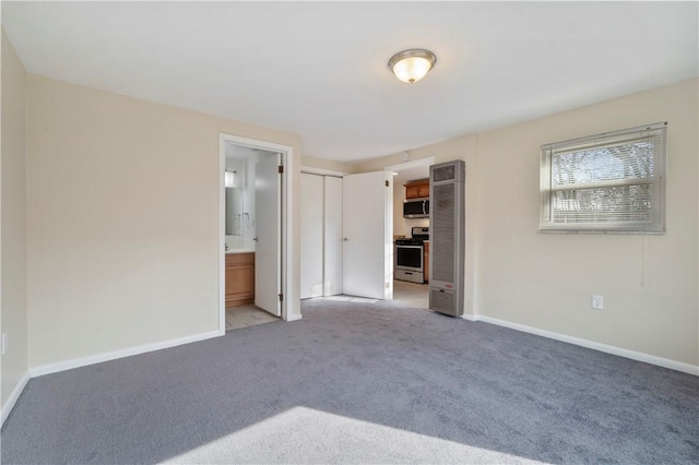 unfurnished bedroom featuring fridge, baseboards, ensuite bathroom, and light colored carpet