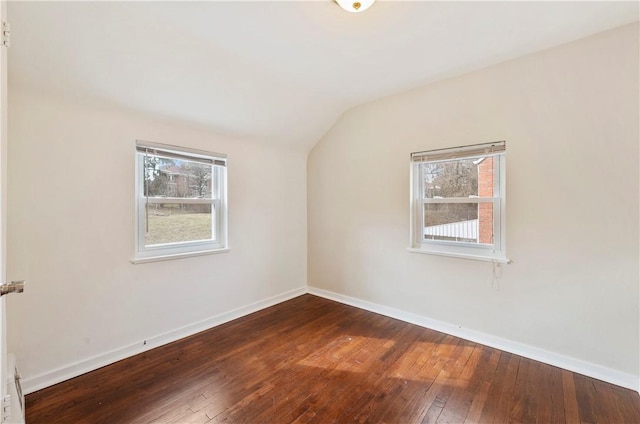 unfurnished room featuring lofted ceiling, dark wood-style flooring, a wealth of natural light, and baseboards