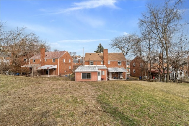 back of house with an outbuilding, a lawn, and a chimney