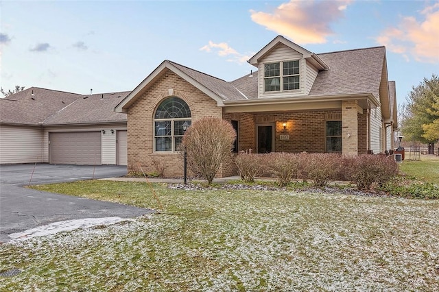 view of front of house featuring a garage, brick siding, driveway, and roof with shingles