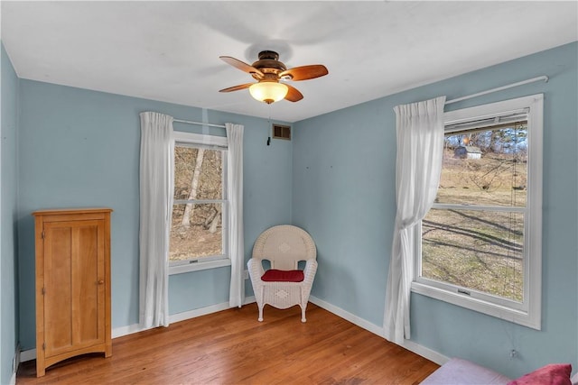 sitting room with a healthy amount of sunlight, visible vents, baseboards, and wood finished floors