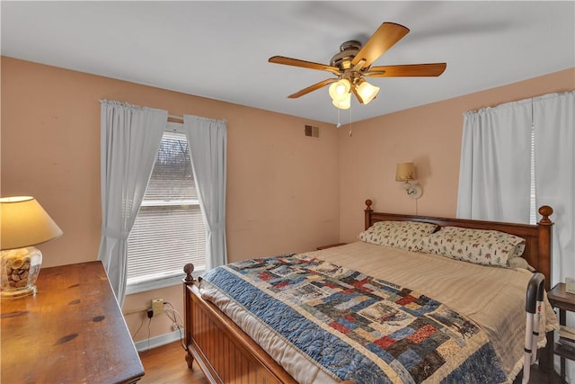 bedroom featuring light wood-type flooring, ceiling fan, visible vents, and baseboards