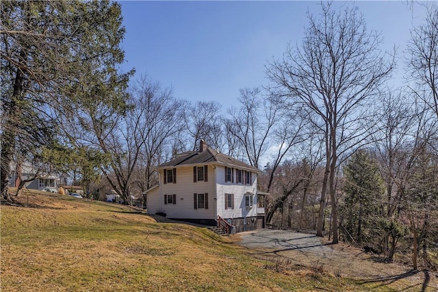 view of side of property featuring a yard and a chimney