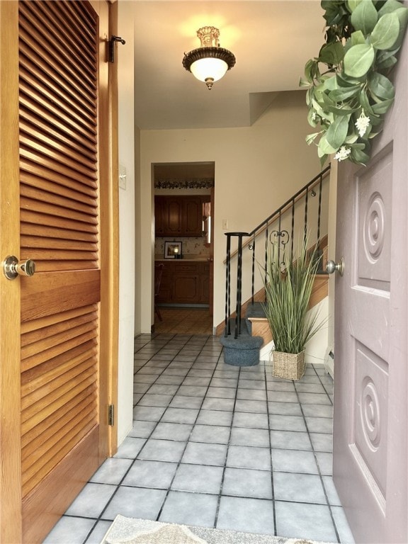 foyer entrance with light tile patterned floors, stairway, and baseboard heating