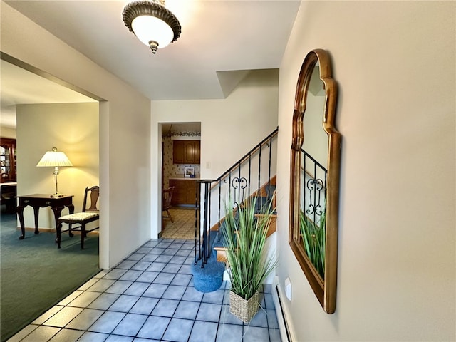 entrance foyer with light carpet, stairs, a baseboard heating unit, and light tile patterned flooring