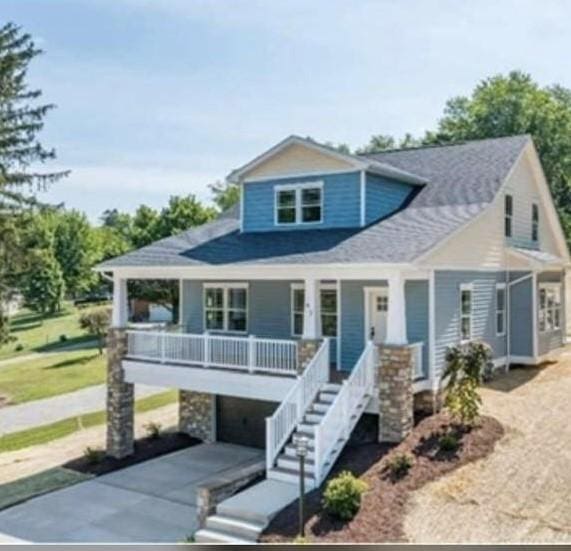 view of front facade featuring stairway, a garage, covered porch, and driveway