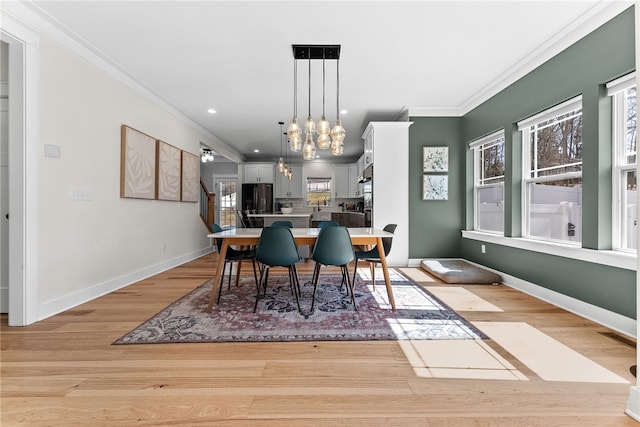 dining area with an inviting chandelier, crown molding, baseboards, and light wood-type flooring