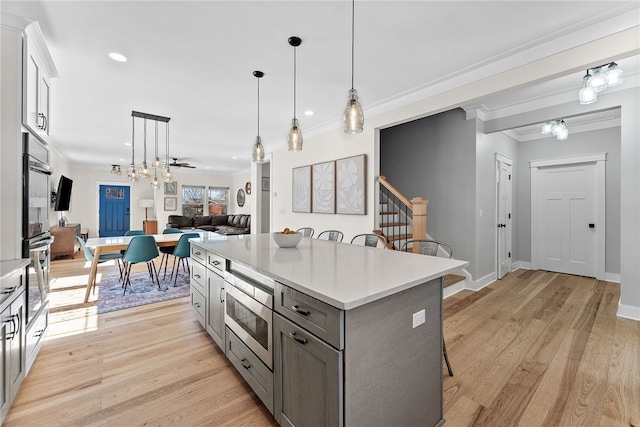 kitchen with ornamental molding, a kitchen breakfast bar, gray cabinetry, and stainless steel appliances