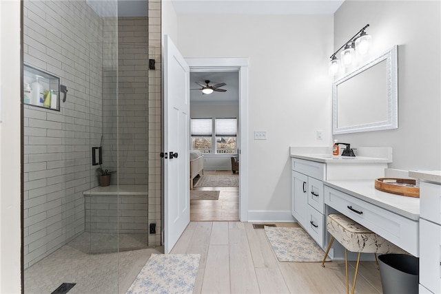 bathroom with a stall shower, wood finished floors, ensuite bath, baseboards, and vanity