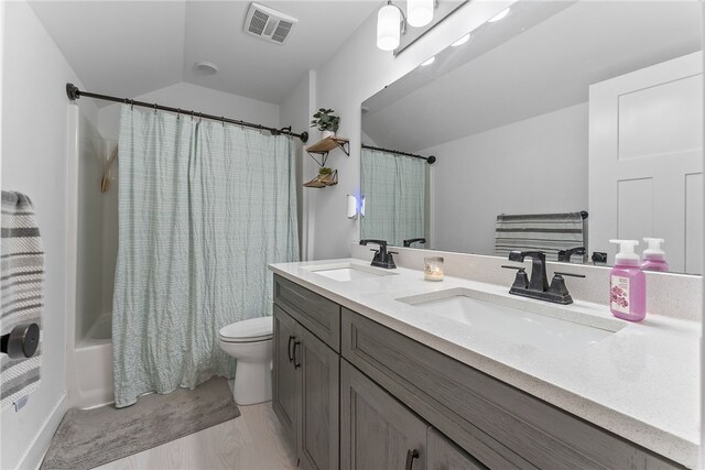 bathroom with lofted ceiling, toilet, visible vents, and a sink