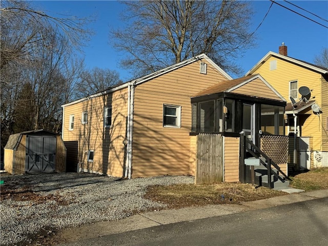 view of front of house featuring a storage shed, an outdoor structure, and a sunroom