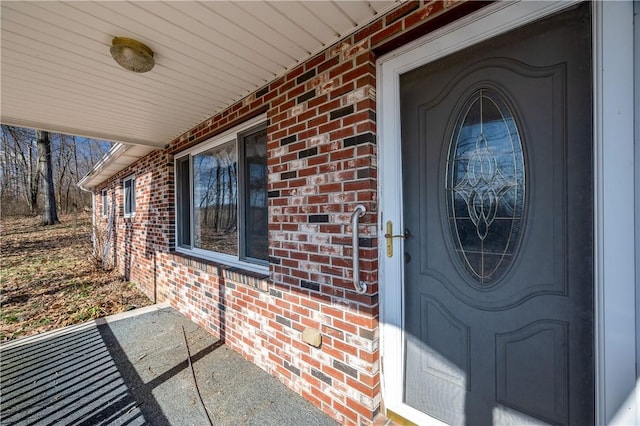 property entrance featuring brick siding and a porch