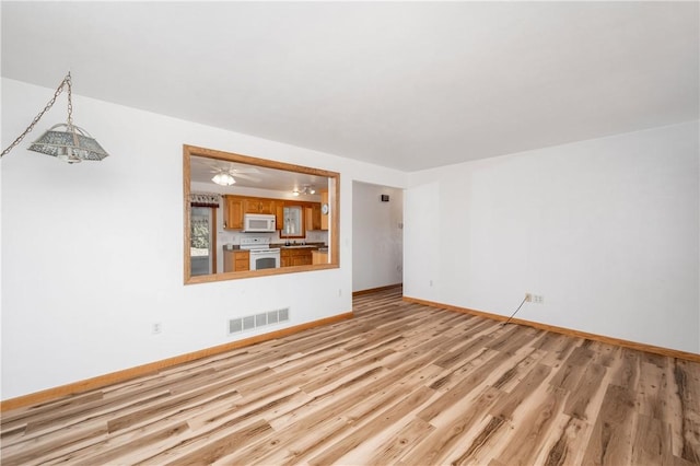 unfurnished living room featuring light wood-style floors, baseboards, and visible vents