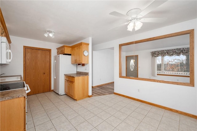 kitchen featuring ceiling fan, white appliances, light tile patterned floors, and baseboards