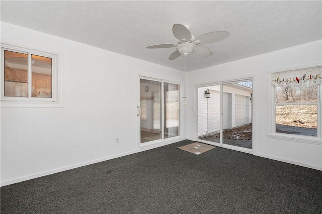 empty room featuring a ceiling fan, dark carpet, and baseboards