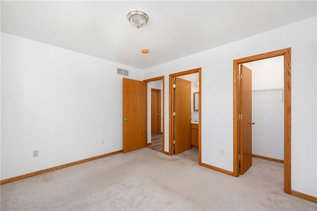 unfurnished bedroom featuring carpet, visible vents, a spacious closet, and baseboards