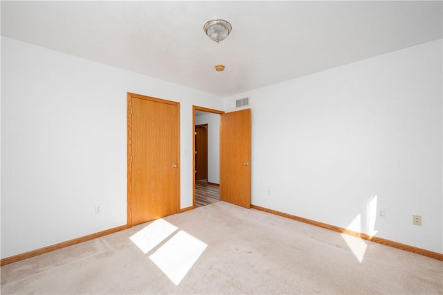 carpeted spare room featuring visible vents and baseboards