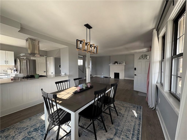 dining space with a fireplace, dark wood-style floors, and baseboards