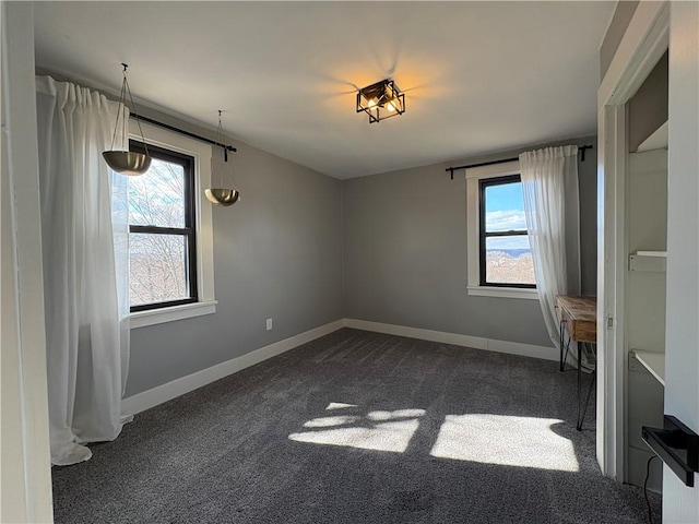 unfurnished bedroom featuring multiple windows, baseboards, and dark colored carpet