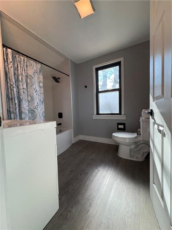 full bathroom featuring shower / bathtub combination with curtain, toilet, wood finished floors, and baseboards