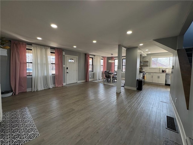 unfurnished living room featuring dark wood finished floors, visible vents, and a wealth of natural light