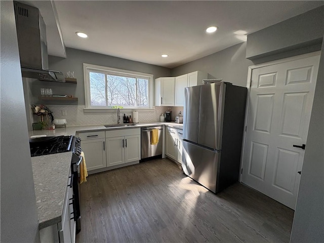 kitchen with backsplash, wall chimney range hood, dark wood finished floors, appliances with stainless steel finishes, and a sink